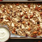 Crunchy vanilla nut granola served in a mason jar with fresh fruit and yogurt.