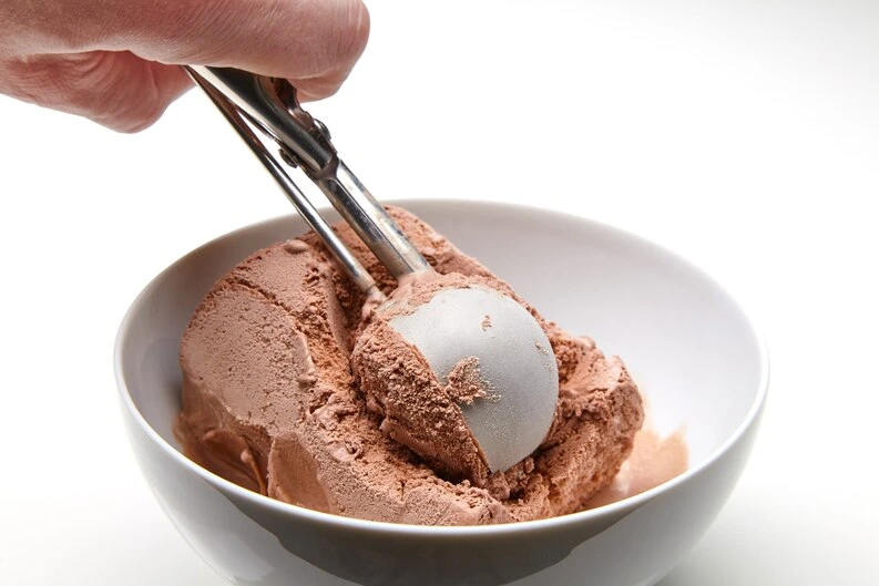 Perfectly rounded scoop of strawberry ice cream being served with a premium ice cream scoop.