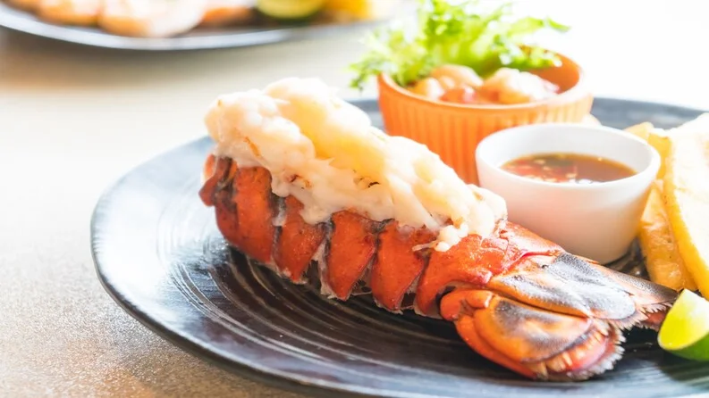 Garlic butter lobster tails on a serving platter with sides.