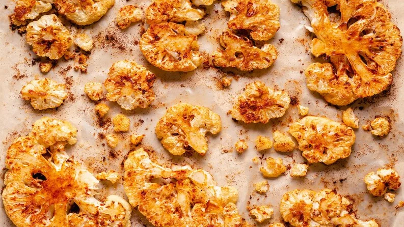 Cauliflower crisps on a plate with fresh vegetables.