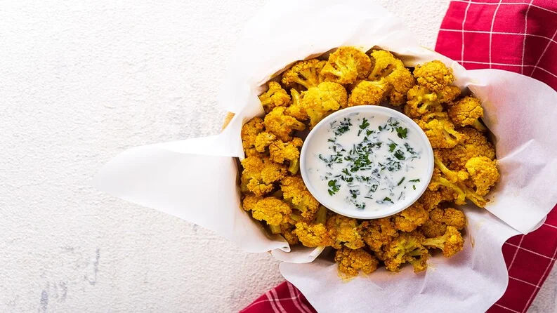 Cauliflower crisps in a bowl with seasonings.